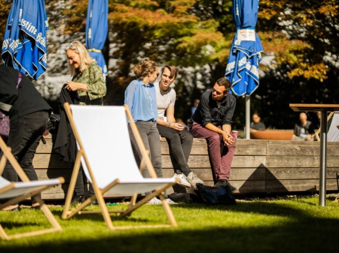  Außenbereich des Festivals, Menschen unterhalten sich und sitzen in der Sonne